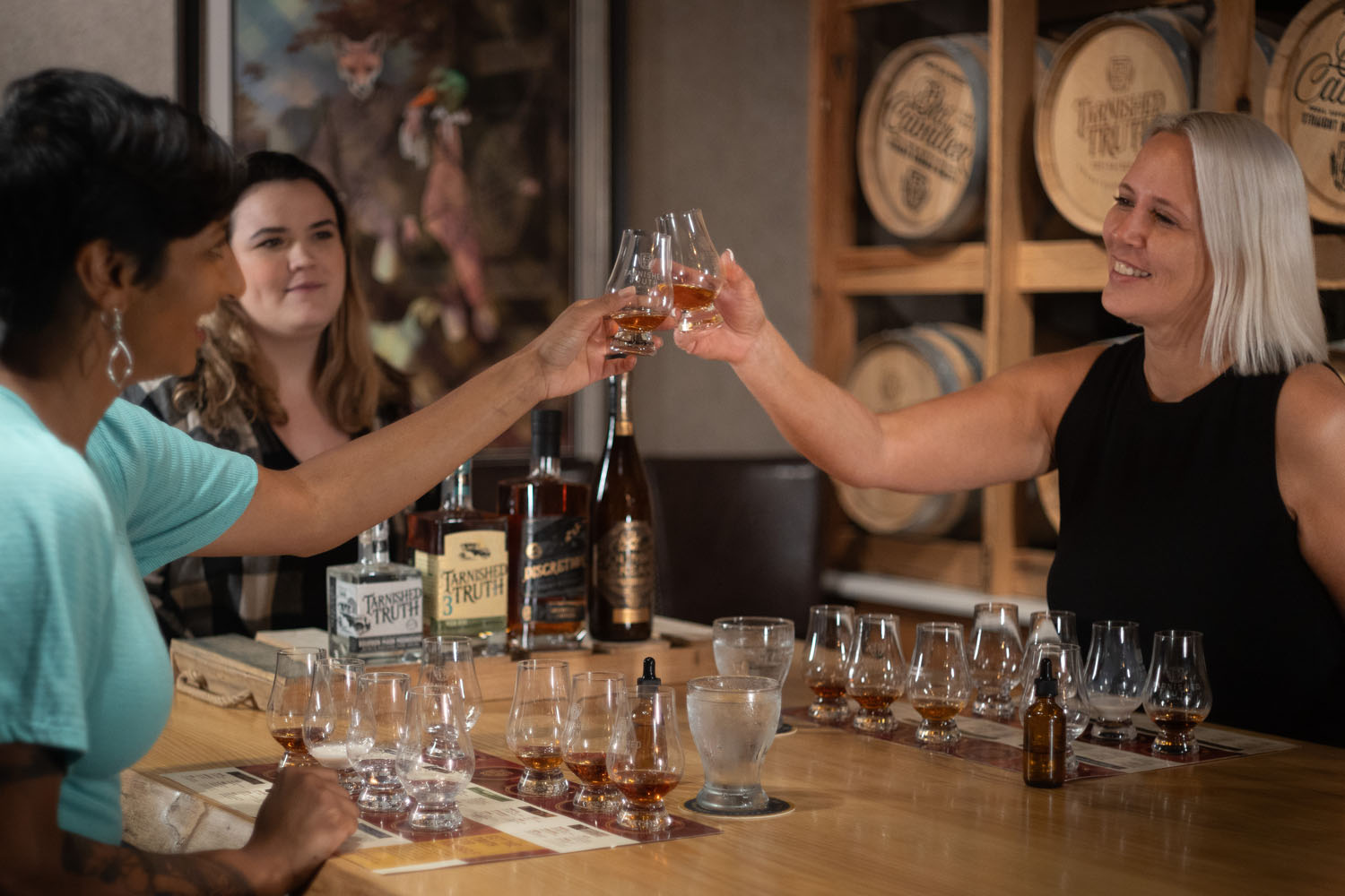 Two women raising glasses during a distillery tour inside The Historic Cavalier Hotel
