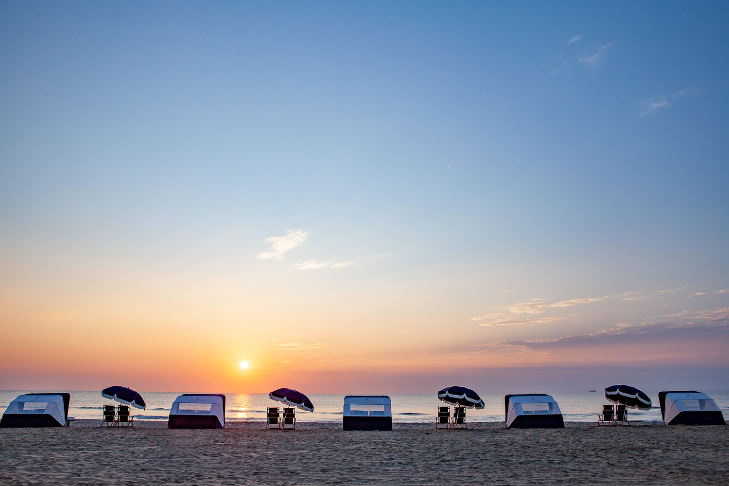 The Cavalier Resort's beach with chairs and cabanas at sunset