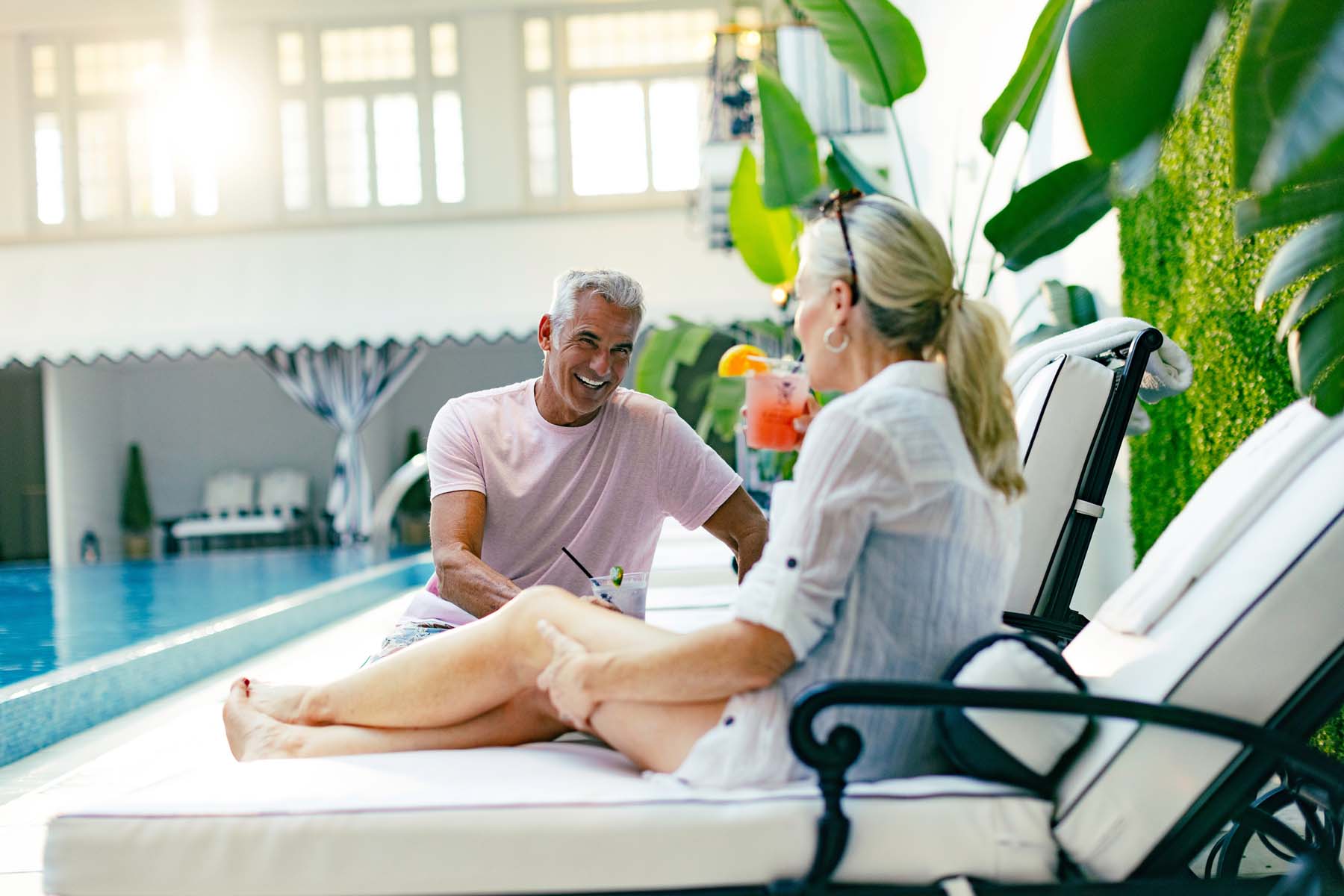 A couple sitting poolside at an indoor pool