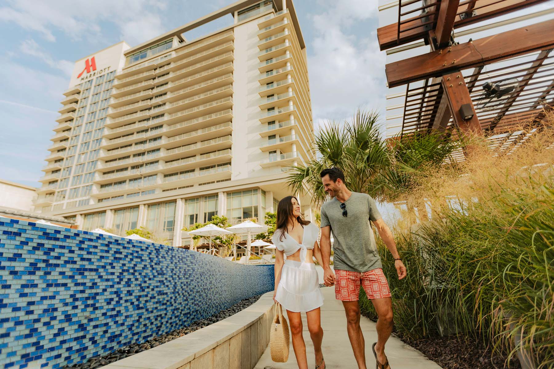 A couple walking outside a Marriott hotel near the beach