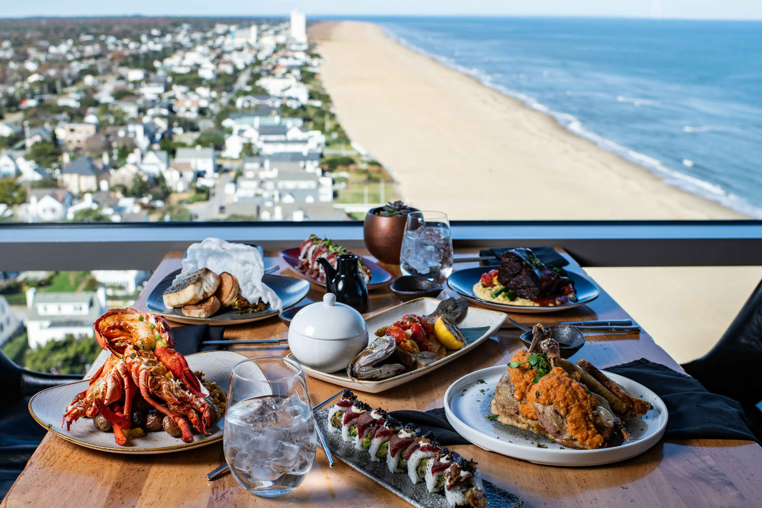 A variety of plated dishes and drinks with ocean views at Orion's Roof restaurant