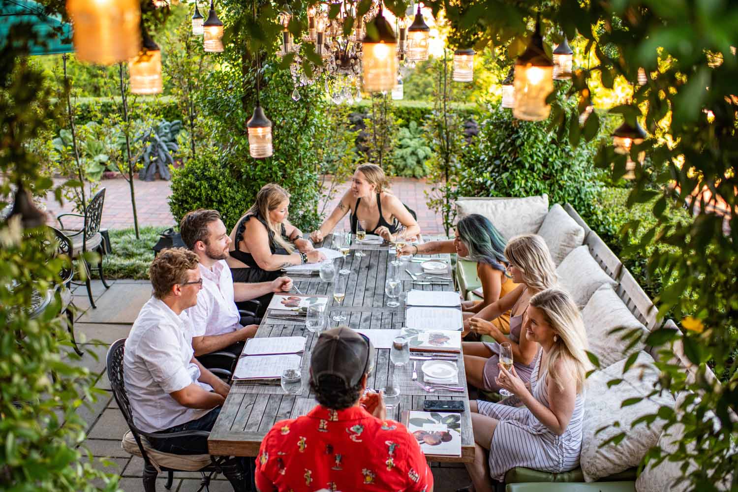 A group of people enjoying a meal outdoors in a garden at the Cavalier Resort Virginia Beach